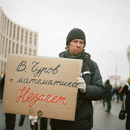 Pavel, engineer, with a sign that may be loosely translated as 'Churov, you failed your maths exam' (Vladimir Churov is the chairman of the Central Election Commission, accused of massive fraud during the last parliamentary elections)