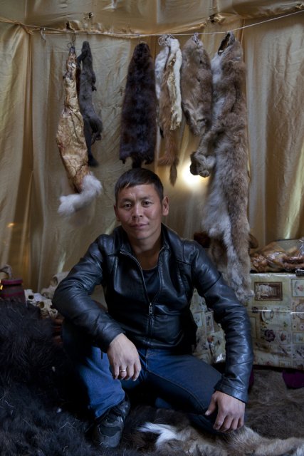 Saidash Kol, 28, a deer farmer and hunter from the Todzha area (northeastern Tuva), poses for picture in his tent he and his workers have built for the yearly Naadym farmers' fest. He also owns a fishery, a cafe and a hotel in his village. Once nomadic deer farmers, Todzha Tuvans no longer live in this kind of tents, preferring village homes, but some of them still know how to build a tent for special occasions such as this Naadym fest. Deer were not brought over though for they pasture deep in the forest during this time of year and their respiratory systems are not used to dusty steppes. Tos-Bulak, Tuva, Russia.
