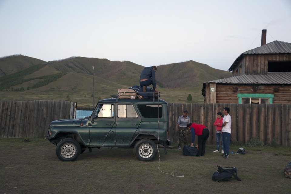 Ertine Bandan (on the roof of the vehicle) unloads the luggage near the home of Bayir-Kys Banchyk - director of the village hall (in red sleeveless jacket) whom he gave a ride - in front of her home in Kachyk, a remote and hard-to-get village near the Mongolian border. The isolated Kachyk sumon (community) has about 300 residents, partly living in the village itself, partly - at nomadic stations in the surrounding valleys. According to Moscow-based sociologist Artemiy Pozanenko who has been studying spacially isolated communities in the post-Soviet world, they tend to be more cohesive and self-sustainable because in part of unlimited access to natural resources around them and absence of regulatory authorities.